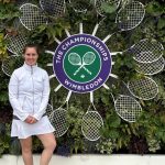 Laura Godfrey in tennis outfit by the Wimbledon sign at Wimbledon Tennis Club